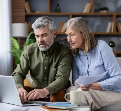 Older couple using laptop to manage finances at home